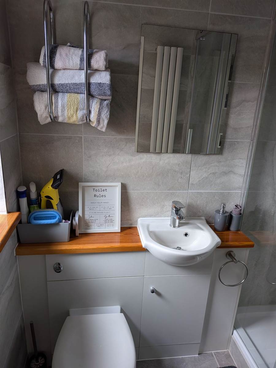 After — finished bathroom with full tiling, vanity unit with pine worktop, mirror and chrome towel rail